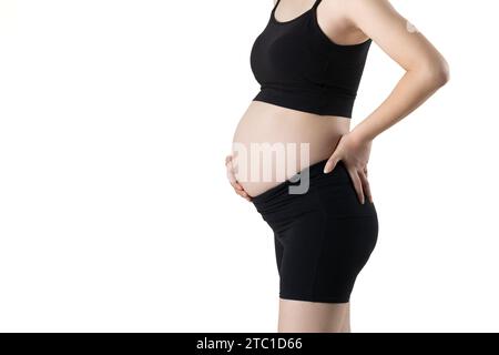 Schwangere Frau, die ihren Bauch herausstreckt und ihn mit den Händen bedeckt (isoliert auf weißem Hintergrund) Stockfoto