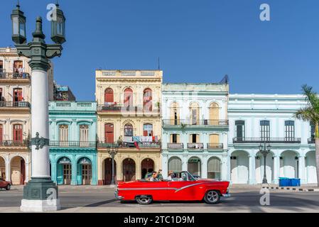 HAVANNA, KUBA - 12. JUNI 2022: Ein klassisches rotes amerikanisches Cabrio, das an bunten Gebäuden im alten havanna, kuba, vorbeifährt Stockfoto