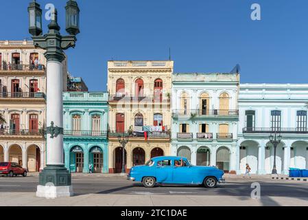 Ein klassisches blaues amerikanisches Auto, das an farbenfrohen Gebäuden im alten havanna, kuba, vorbeifährt Stockfoto