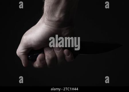 Ein scharfes Messer in der Hand des Mannes. Der Einsatz kalter Waffen. Messerangriff. Bewaffnete Razzia. Stockfoto