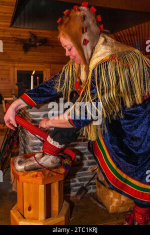 Saariselka, Finnland - 29. November 2010: Samische Frau in traditioneller Kleidung mit Stiefeln aus Rentierfell. Die abgerundete Spitze verhindert ein Stolpern in den s Stockfoto