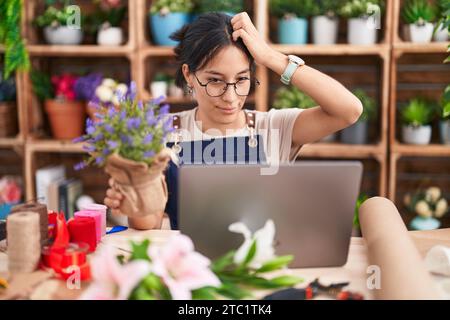 Junge hispanische Frau, die in einem Blumenladen arbeitet, Videoanrufe macht verwirrt und fragt sich über Fragen. Unsicher mit Zweifeln, mit Hand an Kopf denken. Stockfoto