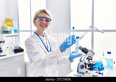 Junge blonde Wissenschaftlerin, die Reagenzgläser im Labor analysiert Stockfoto