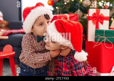 Entzückender Junge und Mädchen, die sich küssen und umarmen und weihnachten zu Hause feiern Stockfoto