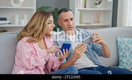 Mann und Frau, die zu Hause auf dem Sofa sitzen und Smartphones benutzen Stockfoto