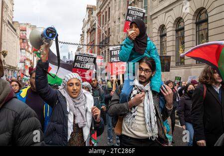 London, Großbritannien. 9. Dezember 2023: Ein Vater trägt seine Tochter, die mit ihrer Mutter bei einer pro-palästinensischen Demonstration für ein Ende Israes aufruft Stockfoto