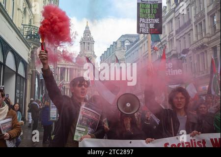 London, Großbritannien. 9. Dezember 2023: Pro-palästinensische Demonstranten halten ein rotes Fackeln und singen bei einer Demonstration, die ein Ende der israelischen Angriffe auf Gaza fordert. Stockfoto