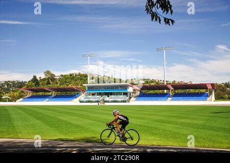 Radfahrerin auf der Strecke & Trafalgar Pavilion Building, Trafalgar Park Rugby Ground, Trafalgar Street, Nelson, Nelson Region, South Island, Neuseeland Stockfoto