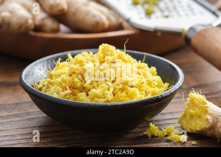 Schüsseln mit geriebenen frischen Ingwerwurzeln. Ganze Ingwerwurzeln und Reibe auf dem Hintergrund. Gesunde Ernährung. Zutaten zum Kochen und Ayurveda. Stockfoto