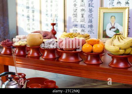 Ein verehrtes Foto eines verstorbenen Verwandten ruht neben einem traditionellen koreanischen Bildschirm mit chinesischer Kalligraphie, als Teil der Charye-Ahnenzeremonie. Stockfoto