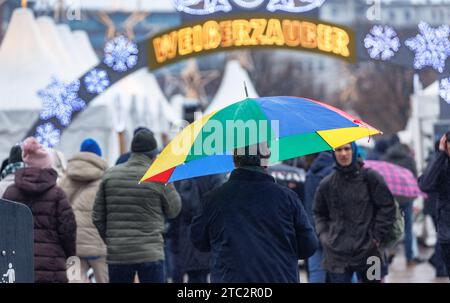 Hamburg, Deutschland. Dezember 2023. Ein Mann läuft mit seinem Schirm durch einen Weihnachtsmarkt im Nieseln. Quelle: Markus Scholz/dpa/Alamy Live News Stockfoto