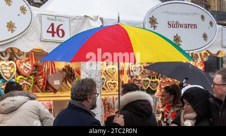 Hamburg, Deutschland. Dezember 2023. Ein Mann läuft mit seinem Schirm durch einen Weihnachtsmarkt im Nieseln. Quelle: Markus Scholz/dpa/Alamy Live News Stockfoto