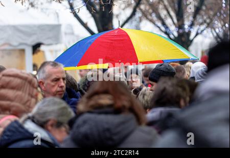 Hamburg, Deutschland. Dezember 2023. Ein Mann läuft mit seinem Schirm durch einen Weihnachtsmarkt im Nieseln. Quelle: Markus Scholz/dpa/Alamy Live News Stockfoto