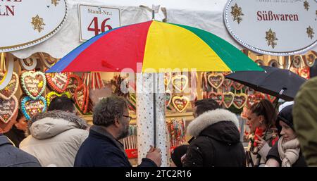 Hamburg, Deutschland. Dezember 2023. Ein Mann läuft mit seinem Schirm durch einen Weihnachtsmarkt im Nieseln. Quelle: Markus Scholz/dpa/Alamy Live News Stockfoto