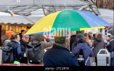 Hamburg, Deutschland. Dezember 2023. Ein Mann läuft mit seinem Schirm durch einen Weihnachtsmarkt im Nieseln. Quelle: Markus Scholz/dpa/Alamy Live News Stockfoto