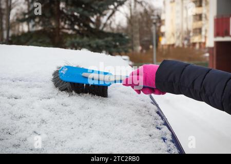 Hand der Frau mit Pinsel und entfernen Schnee von Auto und Windschutzscheibe. Winterprobleme beim Transport Stockfoto