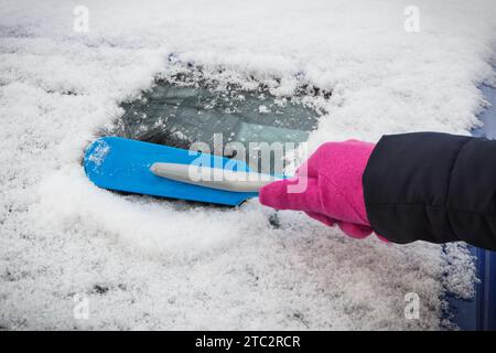 Hand der Frau mit Pinsel und entfernen Schnee von Auto und Windschutzscheibe. Winterprobleme beim Transport Stockfoto