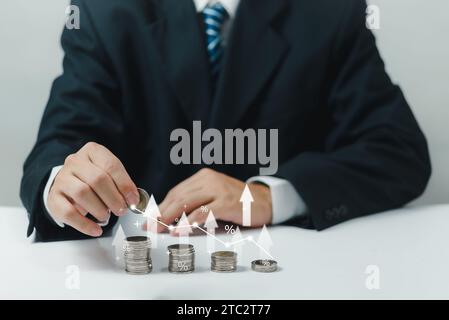 Geschäftsleute, die Münzen mit einem Aufwärtspfeil stapeln, symbolisieren Finanzwachstum durch Ersparnisse, Investitionen und Dividenden, Inflation im Bankwesen. Stockfoto