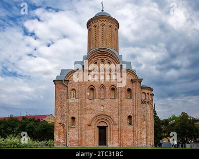 Die Pjatnitskaja-Kirche in Tschernigov, Ukraine, ist ein markantes rotes Backsteingebäude mit einem hohen Turm, das vor einer malerischen Kulisse von üppigem Gier liegt Stockfoto