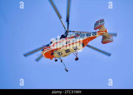 Nahaufnahme eines Löschhubschraubers mit Blick auf die herabhängenden Schläuche vor dem Hintergrund des riesigen blauen Himmels, was seine Bereitschaft zum Feuerlöschhubschrauber unterstreicht Stockfoto