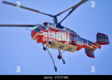 Nahaufnahme eines Löschhubschraubers mit Blick auf die herabhängenden Schläuche vor dem Hintergrund des riesigen blauen Himmels, was seine Bereitschaft zum Feuerlöschhubschrauber unterstreicht Stockfoto