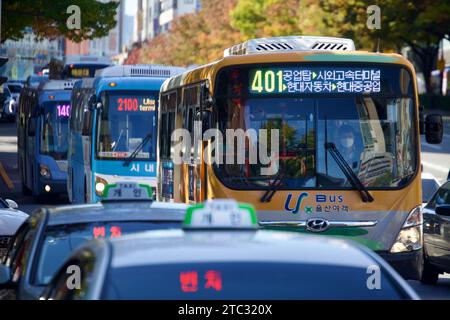 Eine übersichtliche Auswahl an Stadtbussen in Ulsan, die in einem Moment der städtischen Synchronität gefangen sind und den effizienten öffentlichen Nahverkehr der Stadt widerspiegeln. Stockfoto