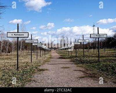 Ein unbefestigter Pfad mit Schildern auf beiden Seiten in einer parkähnlichen Umgebung. Gasse mit den Namen verlassener Dörfer in der Zone der Reaktorkatastrophe von Tschernobyl Stockfoto