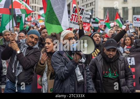 London / Großbritannien - 9. Dezember 2023: Ein pro-palästinensischer muslimischer Demonstrant benutzt ein Megaphon und andere singen bei einer Demonstration, die ein Ende der israelischen Attac fordert Stockfoto