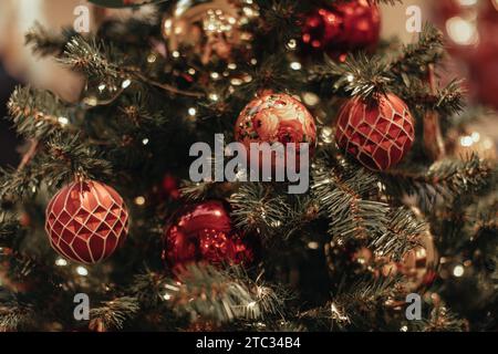 Weihnachtsbaumzweige mit roten, glänzenden Weihnachtskugeln und Lichterketten. Festlicher Hintergrund für Poster, Cover, Broschüre, Postkarte Stockfoto