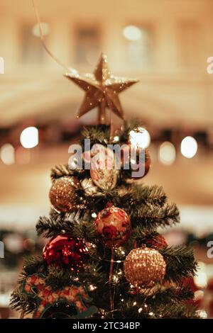 Weihnachtsbäume, dekoriert mit goldenem Stern, roten Weihnachtskugeln, Spielzeug. Festliche Details im Innenraum. Vertikale Postkarte Stockfoto