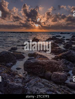 Lebendiger Sonnenuntergang über dem Horizont des Ozeans mit einer felsigen Küste in Sao Martinho do Porto, Portugal Stockfoto