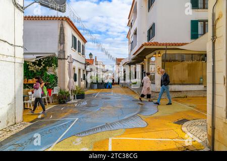 Eine enge Straße mit Straßencafés und Geschäften in der künstlerischen Altstadt von Cascais, Portugal. Stockfoto