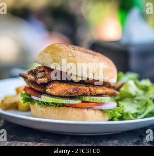 Street Food Fischburger mit Fischkotelett und Gemüse auf weißem Teller. Stockfoto