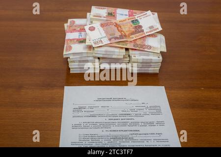 Die Verpackung von fünftausendstel Rubel russischem Geld im Bankpaket liegt in der Form des Kreditvertrags und der Berechnung der Darlehenszahlungen Stockfoto