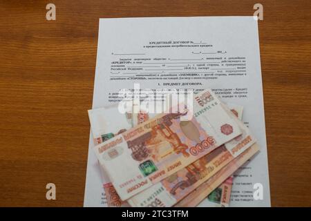 Die Verpackung von fünftausendstel Rubel russischem Geld im Bankpaket liegt in der Form des Kreditvertrags und der Berechnung der Darlehenszahlungen Stockfoto