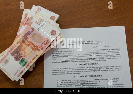 Die Verpackung von fünftausendstel Rubel russischem Geld im Bankpaket liegt in der Form des Kreditvertrags und der Berechnung der Darlehenszahlungen Stockfoto