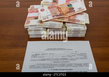 Die Verpackung von fünftausendstel Rubel russischem Geld im Bankpaket liegt in der Form des Kreditvertrags und der Berechnung der Darlehenszahlungen Stockfoto