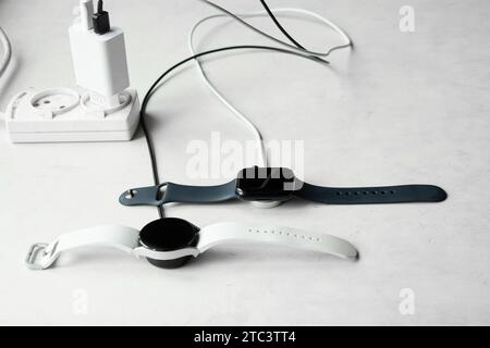 Dnipro, Ukraine - 10. Dezember 2023: Smart Watch Samsung Galaxy Active Watch weiß und schwarz Apple Watch Series 8 liegt auf dem Tisch mit einem Uhrenaufschlag Stockfoto