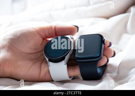 Dnipro, Ukraine - 10. Dezember 2023: Weiße Smart Uhren Samsung Galaxy Active und Apple Watch Series 8 werden von einer weiblichen Hand gehalten, zwei Smart Uhren t Stockfoto