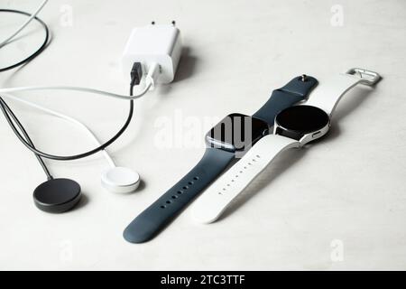 Dnipro, Ukraine - 10. Dezember 2023: Smart Watch Samsung Galaxy Active Watch weiß und schwarz Apple Watch Series 8 liegt auf dem Tisch mit einem Uhrenaufschlag Stockfoto