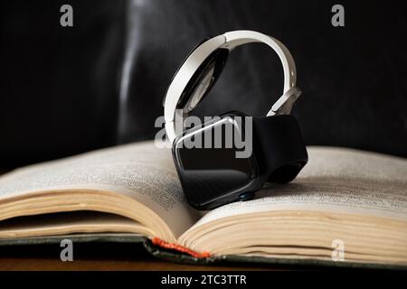 Dnipro, Ukraine - 10. Dezember 2023: Weiße Smart Uhren Samsung Galaxy Active und Apple Watch Series 8 liegen auf dem Tisch zu Hause auf einem Buch, zwei Smart Stockfoto