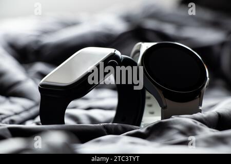 Dnipro, Ukraine - 10. Dezember 2023: Smart Watches Samsung Galaxy Active Watch weiß und Apple Watch Series 8 schwarz liegen auf einem grauen Stoff, Smart Watche Stockfoto