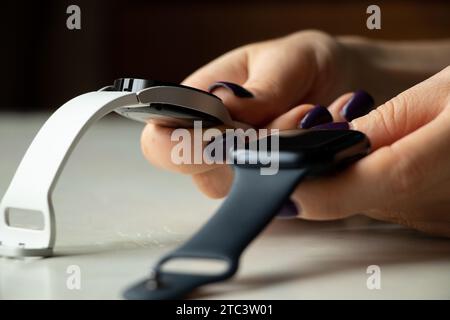 Dnipro, Ukraine - 10. Dezember 2023: Weiße Smart Uhren Samsung Galaxy Active und Apple Watch Series 8 werden von einer weiblichen Hand gehalten, zwei Smart Uhren t Stockfoto