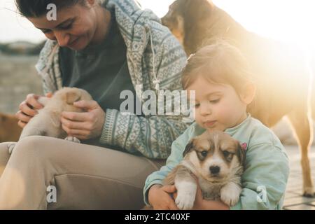 Eine Frau und ihre Tochter halten kleine Hunde in den Armen, umarmt. Zeit für die Familie, Freundschaft mit Tieren Stockfoto