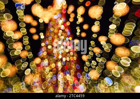 Weihnachten und frohes neues Jahr, verschwommenes Bokeh. Authentische Aufnahme von farbenfrohem Licht auf dem Weihnachtsbaum im Freien mit Bokeh. Wunderschönes weihnachtsbokeh im Hintergrund Stockfoto