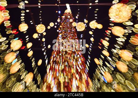 Weihnachten und frohes neues Jahr, verschwommenes Bokeh. Authentische Aufnahme von farbenfrohem Licht auf dem Weihnachtsbaum im Freien mit Bokeh. Wunderschönes weihnachtsbokeh im Hintergrund Stockfoto