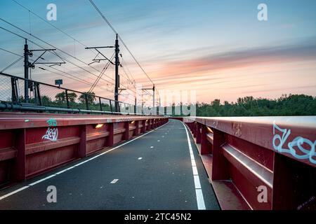 Rote Eisenbahnbrücke namens „Hanzeboog“ über den Fluss IJssel im niederländischen Delta Stockfoto