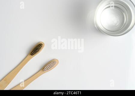 Glaswasser und zwei hölzerne Zahnbürsten Badezimmer auf weißem Hintergrund Stockfoto