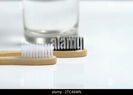 Glaswasser und zwei hölzerne Zahnbürsten Badezimmer auf weißem Hintergrund Stockfoto