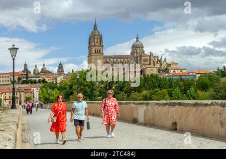 Menschen gehen über die mittelalterliche römische Brücke von Salamanca über den Fluss Tormes mit Blick auf die neue Kathedrale von Salamanca im Hintergrund Spanien Stockfoto